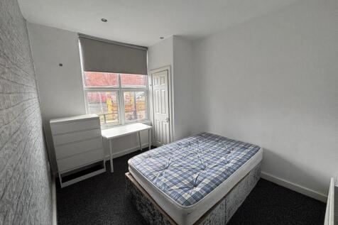 A well-lit student bedroom featuring a single b...