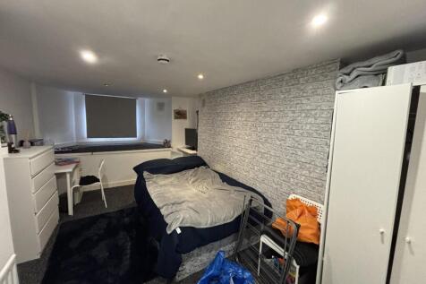 A modest bedroom with a single bed, some storag...