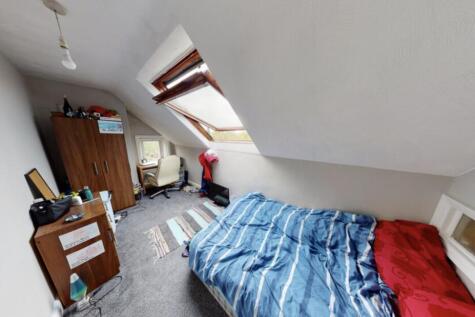 A cozy bedroom with a sloped ceiling, featuring...