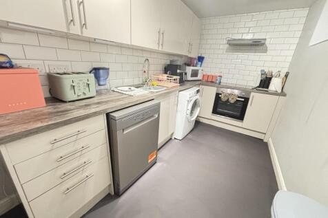 A modern kitchen with white cabinets and applia...