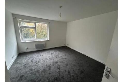 Bright, neutrally decorated bedroom with a larg...