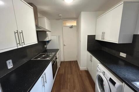Bright, modern galley kitchen with white cabine...