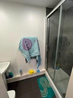 Compact modern bathroom featuring a glass-enclo...