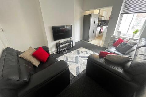 Bright, modern living room with two black leath...
