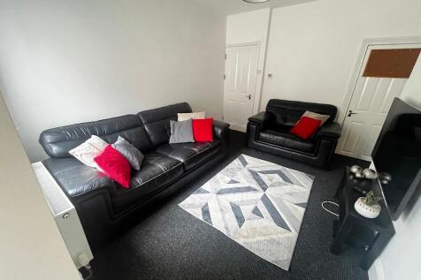 Bright, tidy living room with black leather sof...