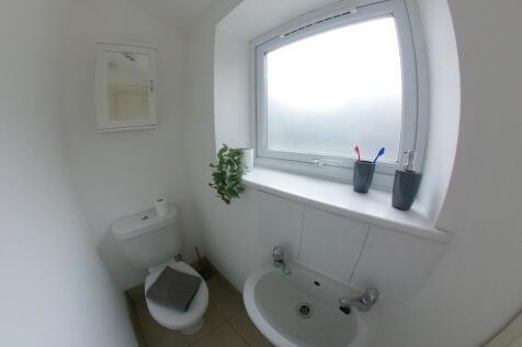 Bright, clean bathroom with white walls, froste...