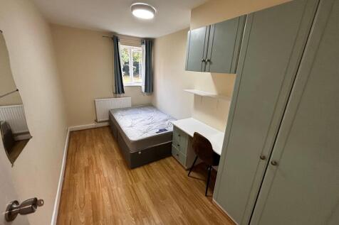 A cozy single bedroom with a tidy bed, ample na...