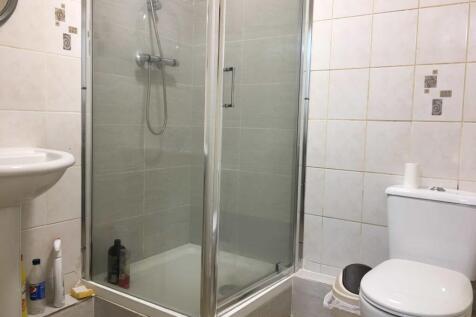 Bright tiled bathroom with a corner glass showe...