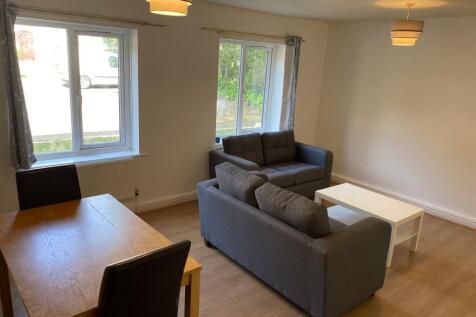 Bright, modern living room with two grey sofas,...