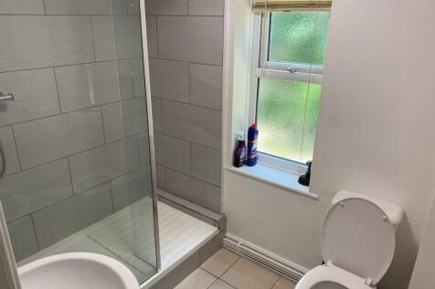 Bright tiled bathroom with an enclosed shower, ...