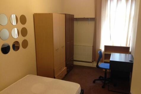 A cozy student bedroom featuring a bed, small d...