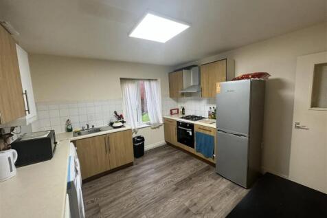 Well-lit kitchen featuring wooden cabinets, a m...