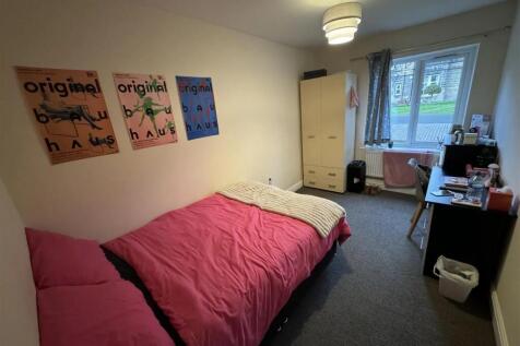 A cozy bedroom featuring a pink bedspread, a wa...
