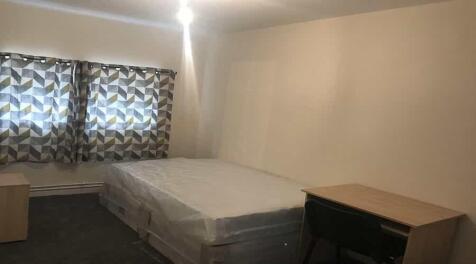 A bright and simple double bedroom with a large...