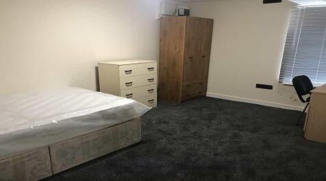 A simple, tidy bedroom featuring a single bed w...