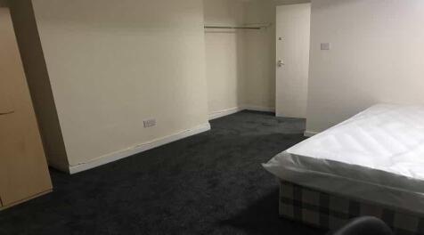 A minimalistic room with a bed partially visibl...