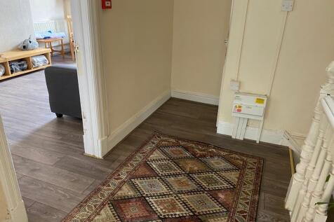 A tidy hallway with wooden flooring and a decor...
