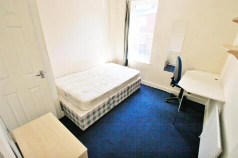 A small, tidy room with a single bed and a wind...