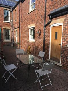 Sunny paved courtyard with a glass-topped outdo...