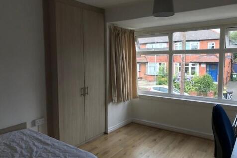 A bright and tidy bedroom featuring a large win...