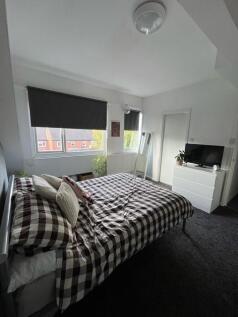 A cozy bedroom featuring a double bed with chec...