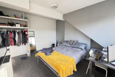 A well-lit bedroom featuring a double bed, a de...