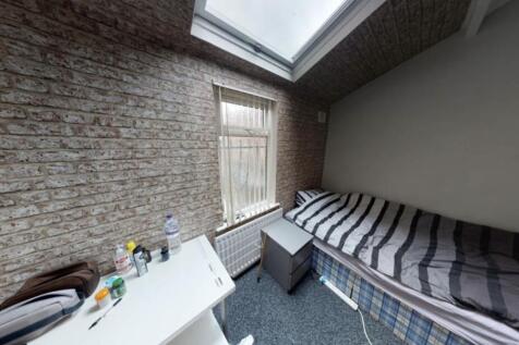 A cozy bedroom featuring a single bed with stri...