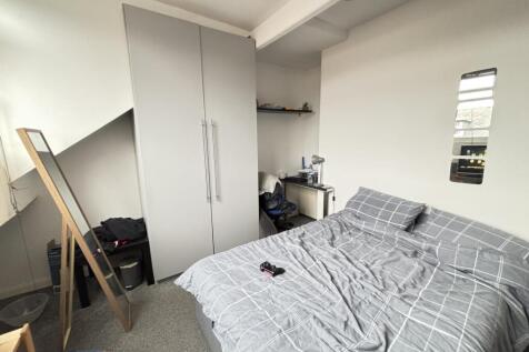 A cozy bedroom featuring a neatly made bed with...