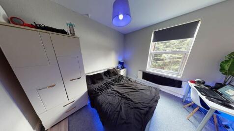 A well-lit bedroom featuring a double bed posit...