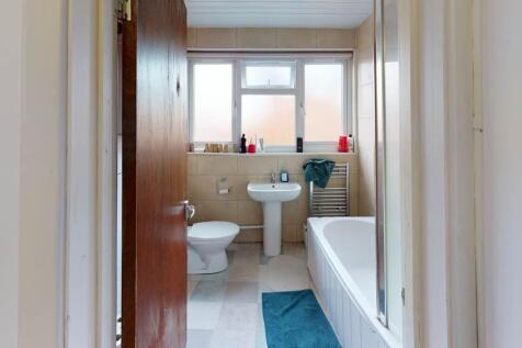 A clean, well-lit bathroom featuring a bathtub,...