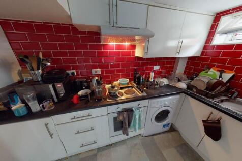 Compact, modern kitchen with glossy red tiled s...