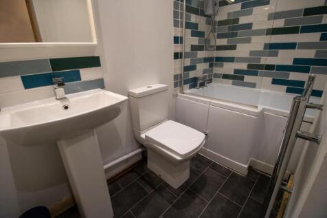 Modern bathroom with patterned tiled bath surro...