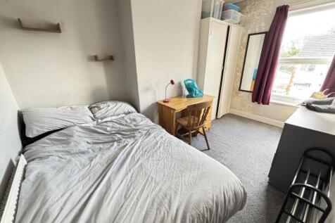 A cozy bedroom featuring a neatly made bed with...