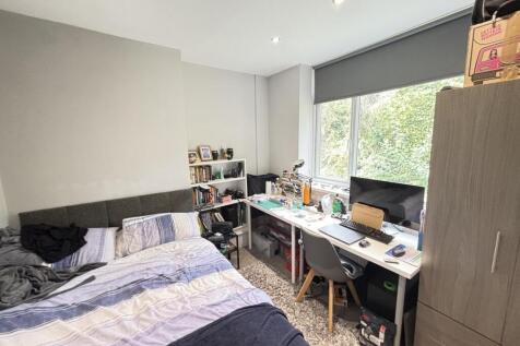 A well-lit bedroom featuring a large window all...