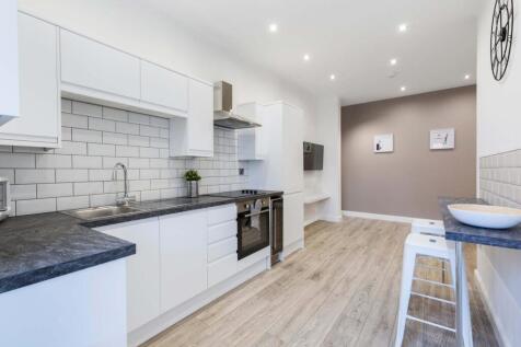 Bright modern kitchen with white cabinetry, sub...