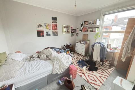 A lived-in bedroom with a bed, clutter on the f...