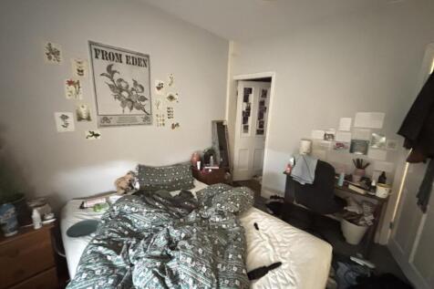 A cozy bedroom with a slightly cluttered bed ar...