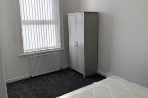 A clean and simple room with a white door and a...