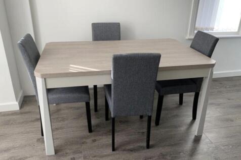 Bright, modern dining area with a light wood ta...