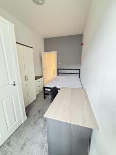 A cozy bedroom featuring a double bed, a desk w...