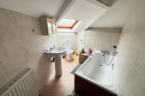 A bright and tidy bathroom with a bathtub and a...