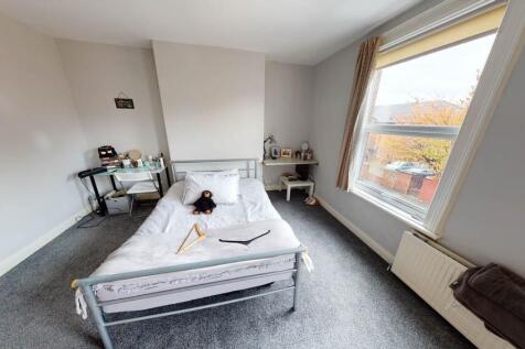 A bright and tidy bedroom featuring a comfortab...