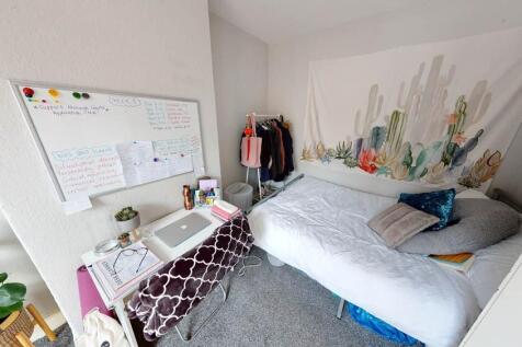 A bright and tidy student bedroom featuring a c...