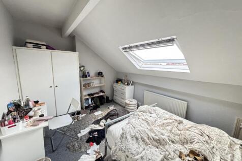 A cozy bedroom with a sloped ceiling and a skyl...