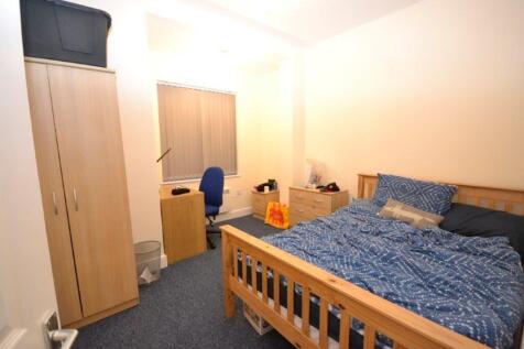 A tidy double bedroom featuring a bed, desk, an...