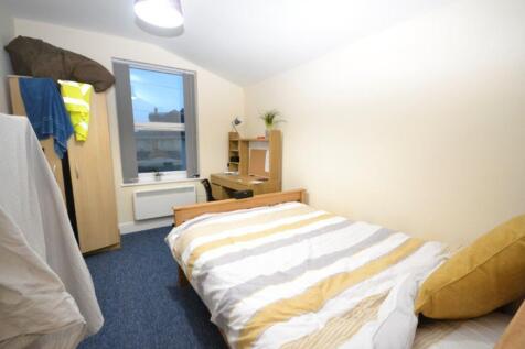 A cozy double bedroom with a bed, desk, and war...