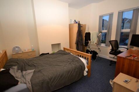 A tidy double bedroom with a bed, desk, and nat...