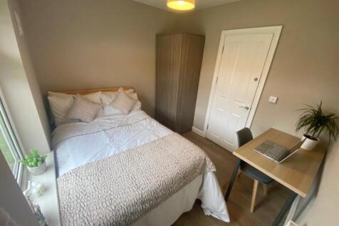 A clean and well-lit double bedroom with a fitt...