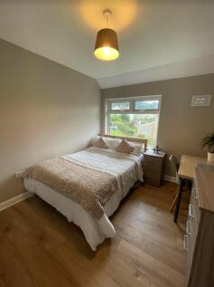 A clean and well-lit double bedroom with a cozy...