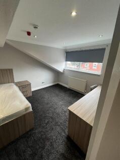 A bright, modern bedroom with a sloped ceiling,...